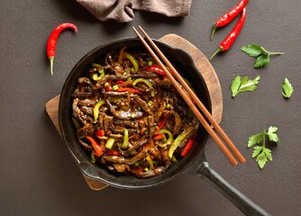 Fried thinly sliced beef steak with peppers in cast iron skillet