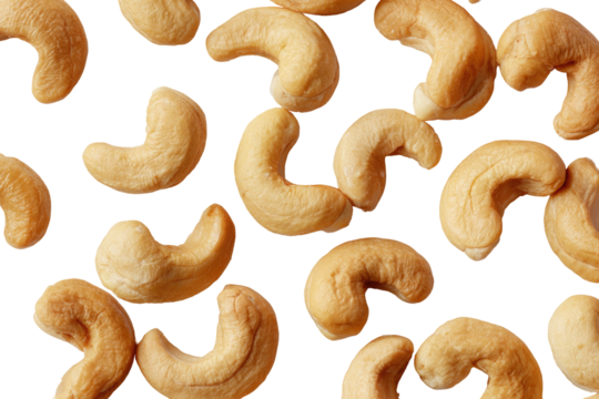Close-up of shelled cashew nuts scattered on a stark black background