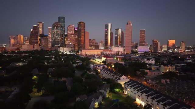 Aerial drone shot captures the dramatic Houston, Texas, skyline at twilight, showcasing the city's modern architecture and vibrant illumination during the 'blue hour.'