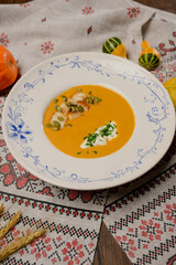 Pumpkin cream soup with seeds, cream, and parsley on a plate