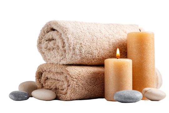 Beige rolled towels, glowing candles, and smooth gray stones compose a relaxing spa-like scene