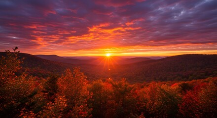 Obraz premium Vibrant Autumn Sunrise Over Rolling Hills and Forest Canopy in Fiery Colors