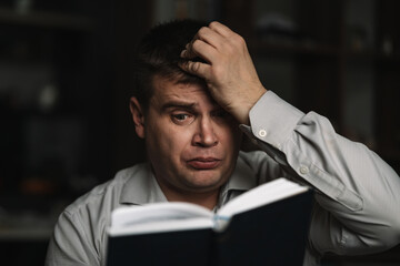 leisure, literature and people concept man sitting on sofa and reading book at home. reader is...