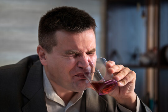 caucasian businessman alcoholic wearing a blue work shirt and tie drunk and drinking Scotch or Whiskey sitting at home after a long day or week of work on a white background.