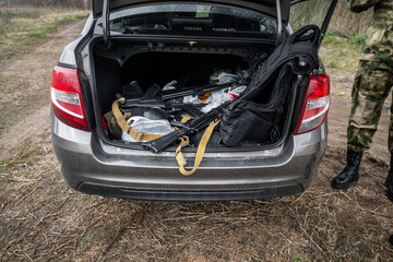 Arms trafficking. different rifles. clandestine sale of weapons. illegal deal to sell weapons. A man pulls an assault rifle out of a car. The concept of arms smuggling.