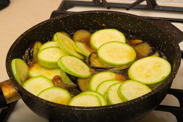 Zucchini cut into rings are fried in a frying pan in oil