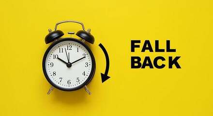 A classic black alarm clock is set against a vibrant yellow background with the words fall back and an arrow, signifying the end of daylight saving time