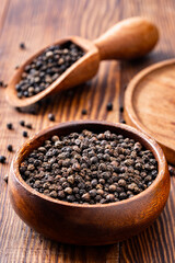 Black peppercorns on wooden background	