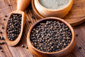 Black peppercorns and ground black pepper powder on wooden background	