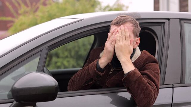 Portrait of shocked young man sitting in his car, looking at camera.