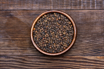 Black peppercorns on wooden background	
