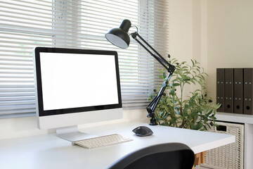 Side view of computer monitor, white screen mockup placed on table, inside office room.