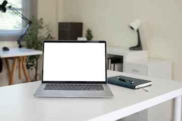 Front view with laptop placed on white table and notebook