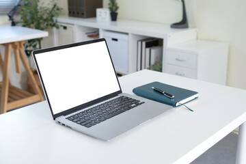 Side view with laptop on white table and notebook
