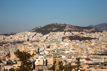 Fototapeta premium Cityscape of Athens with Lycabettus Hill under clear blue skies.