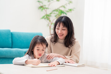 幼稚園児の女の子と一緒に勉強をするお母さん