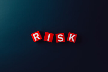 Risk management and business uncertainty concept with red cubes spelling the word RISK on dark background, symbolizing uncertainty, financial decision-making, business strategy for problem prevention,