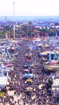 Aerial of Oktoberfest in Munich with roller coaster and tight crowd - urban folk festival in lively sunny Bavarian atmosphere scenery - symbol of tradition and modern culture - Germany 2025-09-21