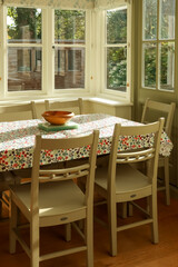 Dining table set with a floral tablecloth and chairs in a bright, cozy home interior. Cotswolds countryside, England