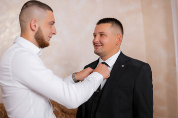 Groom getting ready with best man in formal outfit before wedding ceremony