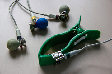 An electrode and a clamp for an electrocardiograph are on the table. On a gray background.