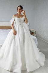 Fototapeta premium Elegant bride poses in a stunning white wedding dress in a bright, cozy room
