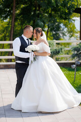 Couple shares a tender moment during their outdoor wedding ceremony in a sunny garden