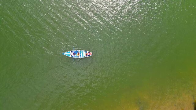 Aeria view of a man rowing a traditional canoe, known as &ldquo;catraia,&rdquo; transporting bathers from the village to the beach of Alter do Chao, along the Tapajos river in Santarem, Para, Brazil