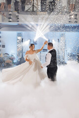Wedding couple dances together in a cloud of fog during a lively celebration