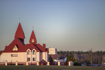 Architectural structure featuring a unique design with red roofs and spires, surrounded by a fence...