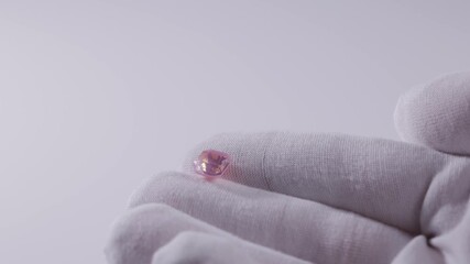 Closeup of pink sapphire gemstone on gloved hand against white background. - Powered by Adobe