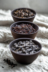 Three bowls of different grains and seeds on a textured surface