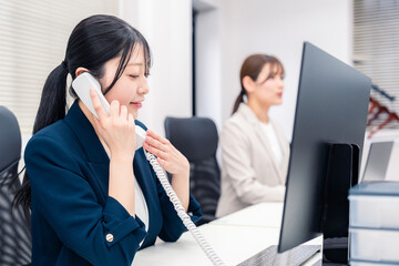 Fototapeta premium オフィスでにこやかに電話対応をするビジネスウーマン