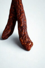 Close up of two dried sausages on a white surface