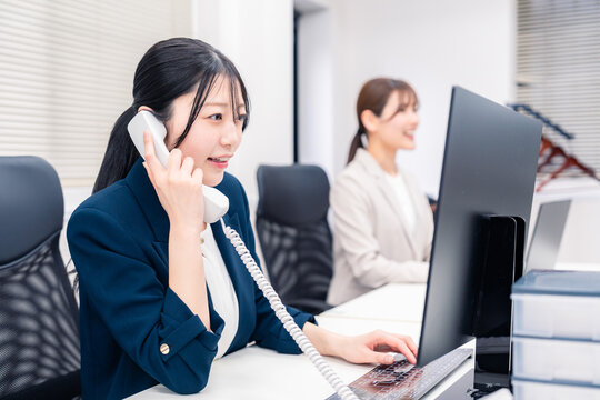 オフィスでにこやかに電話対応をするビジネスウーマン