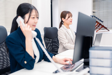 Fototapeta premium オフィスでにこやかに電話対応をするビジネスウーマン