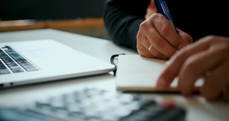 Close-up of male hands writing notes in notebook next to laptop, creative planning or studying concept in soft natural light. - Powered by Adobe