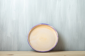 A ceramic plate stands on a wooden table against a gray background.