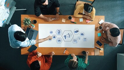 A dynamic group of diverse professionals collaborates in a productive meeting, brainstorming and planning strategies around a large table in a modern office environment. Raster