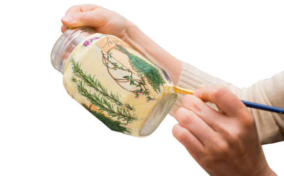 Decoupage bottle. The artist's hands with a brush paint on the bottle