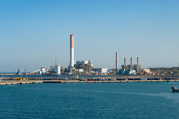 Coal-fired power plant with tall smokestacks in the port of Civitavecchia, Italy.
