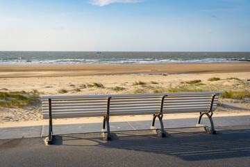 Park bench on the shore of North Sea. Wind makes structures in the sand at the ocean, natural art on the sandy beach, place to recreation on holiday