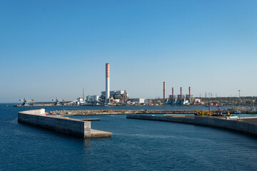 Coal-fired power plant with tall smokestacks in the port of Civitavecchia, Italy.