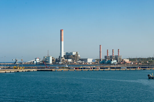Coal-fired power plant with tall smokestacks in the port of Civitavecchia, Italy.