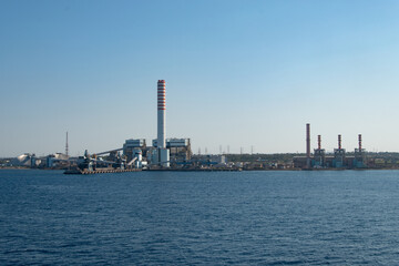 Coal-fired power plant with tall smokestacks in the port of Civitavecchia, Italy.