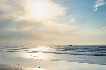 single ship is sailing on the North Sea, ship, sails and waves shine in the evening light, North Sea beach before sunset with waves of the ocean