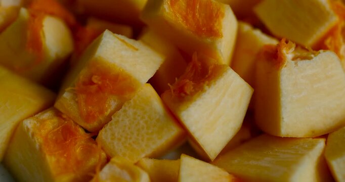 Close-up of fresh pumpkin cubes showing vibrant orange color and juicy texture. Ideal for autumn cooking, healthy recipes, and seasonal vegetable preparation