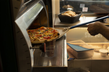 Chef hands preparing pizza, showing dough, sauce, and ingredients in process without visible face, reflecting culinary craftsmanship and traditional Italian cooking.