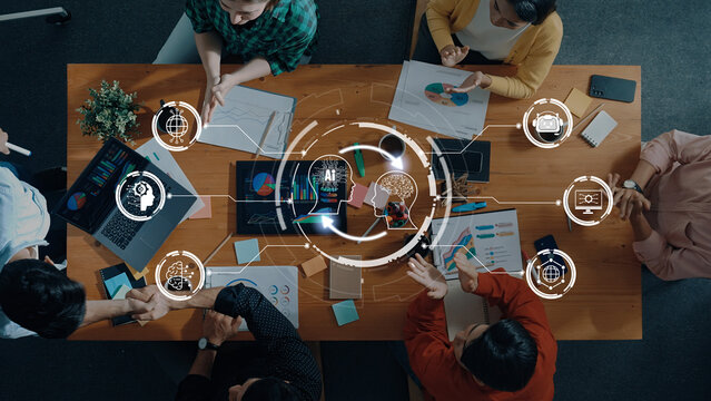 A business team collaborates in a modern office, analyzing data charts and discussing strategies during a meeting. Technology and teamwork drive innovation and planning. Trope