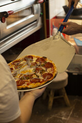 A delicious pizza is now being freshly served directly from an oven using a pizza peel in a busy restaurant